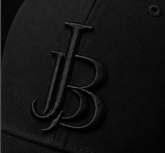 Close-up of the tonal black JB monogram embroidery on the Drop 01 cap